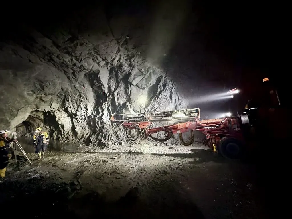 A drill crew working a lit heading underground at a partner mine.